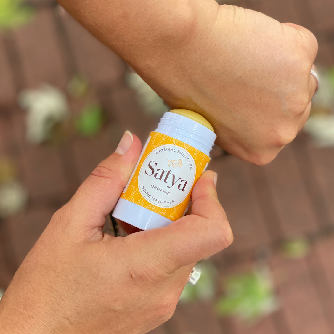 A person applying the Satya Eczema Relief Easy Glide Stick to their hand.
