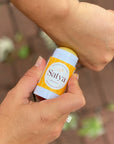 A person applying the Satya Eczema Relief Easy Glide Stick to their hand.