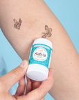 A person applying the Satya Multi Use Easy Glide Stick to their arm as tattoo aftercare.