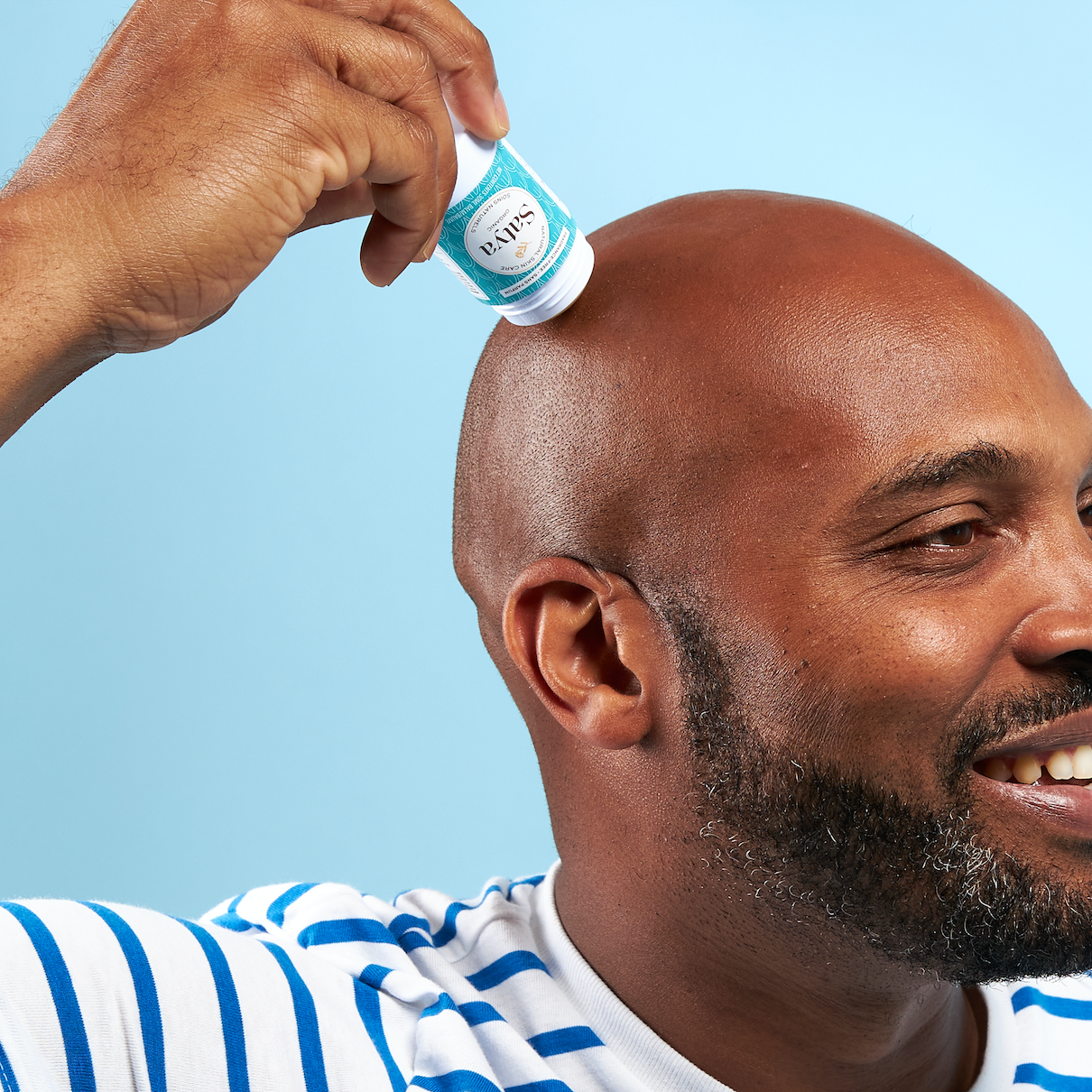 A person applying the Satya Multi Use Easy Glide Stick to their scalp.